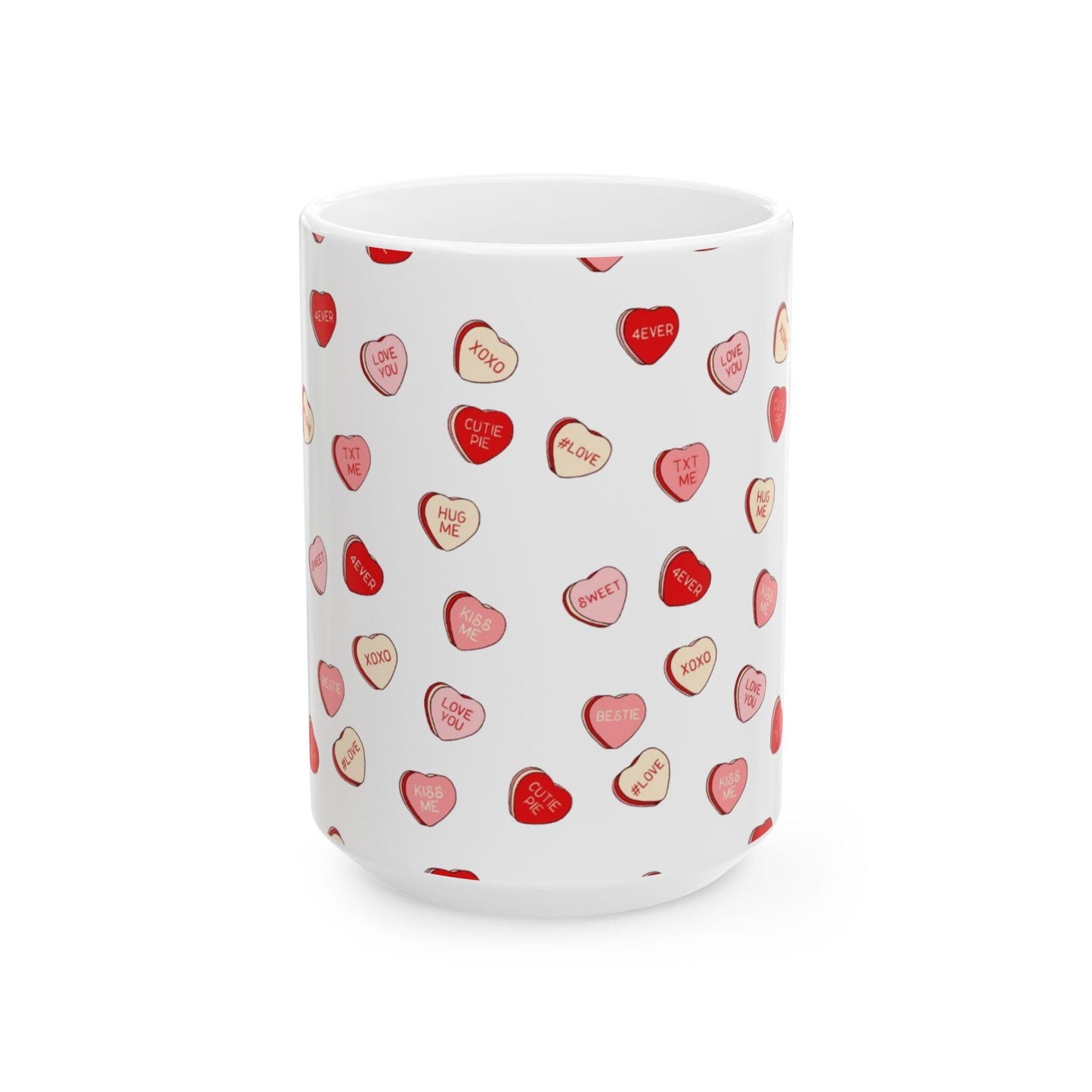 A white ceramic coffee mug with a hand-drawn design of red conversation hearts with different words like 'love', 'hug', and 'kiss'.