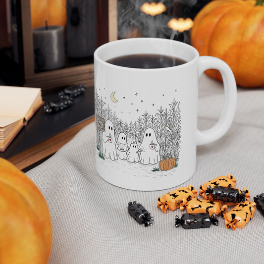 White ceramic coffee mug printed on both sides with a hand-drawn ghost family walking through a moonlit corn maze with warm drinks and a pumpkin, from The Story of the Ghost Chapter 2 collection.