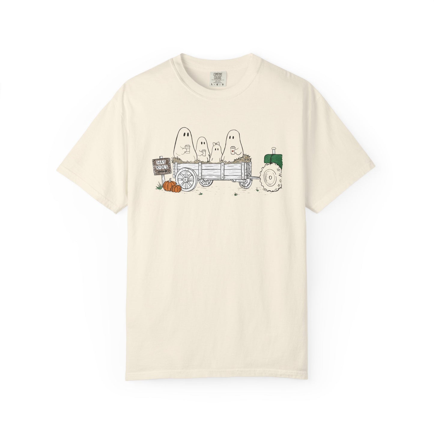 Comfort Colors ivory t-shirt featuring a hand-drawn ghost family riding in a hay wagon with pumpkins, coffee mugs, and a vintage tractor from The Story of the Ghost Chapter 1 collection.