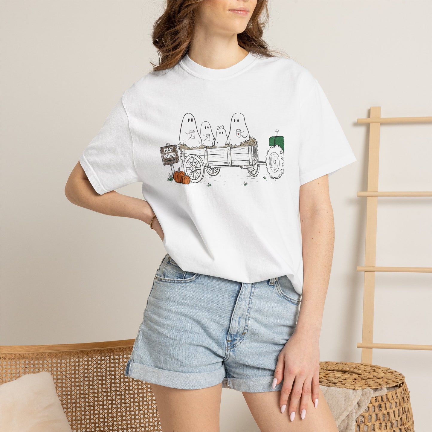 Comfort Colors white t-shirt featuring a hand-drawn ghost family riding in a hay wagon with pumpkins, coffee mugs, and a vintage tractor from The Story of the Ghost Chapter 1 collection.
