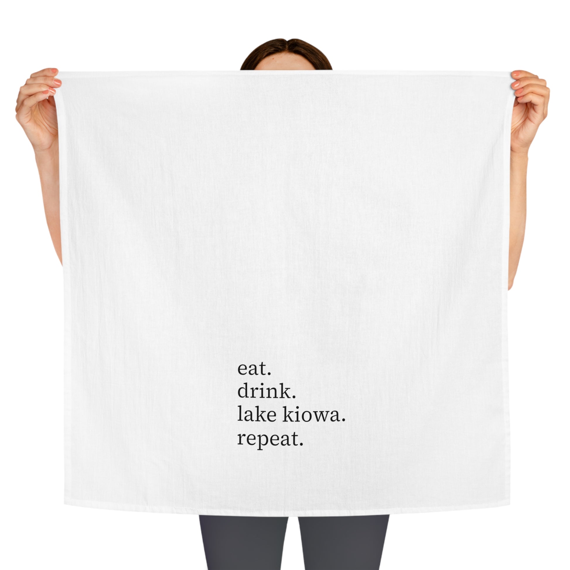 Person holding a white towel with text 'eat. drink. lake kiowa. repeat.'