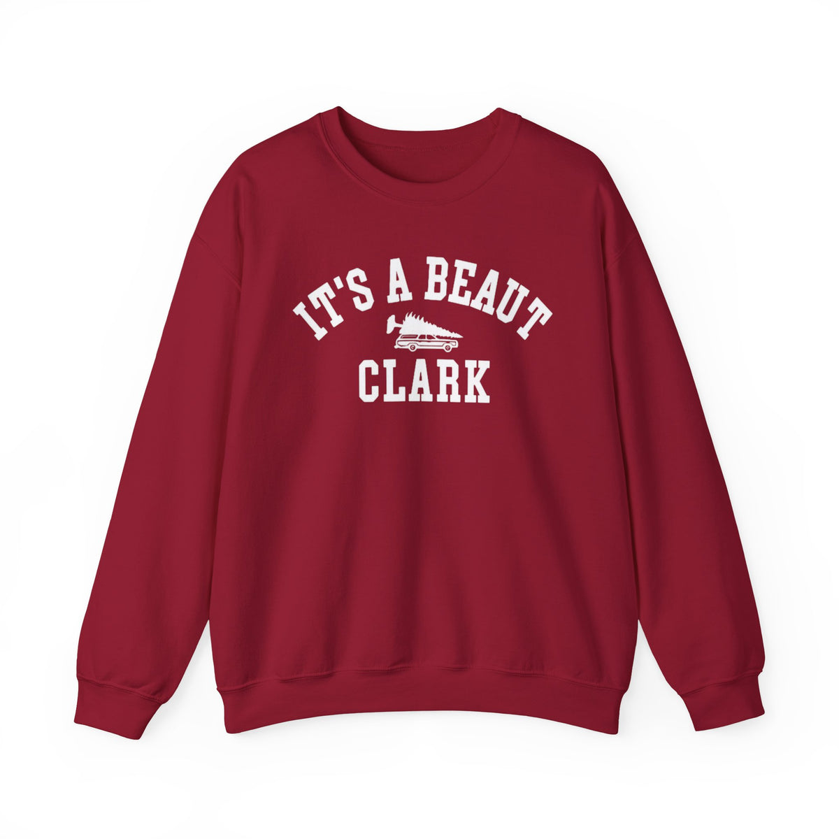 A maroon crewneck sweatshirt with 'IT'S A BEAUT CLARK' printed in white arched text across the chest, featuring a small white wagon with a Christmas tree graphic in the center.