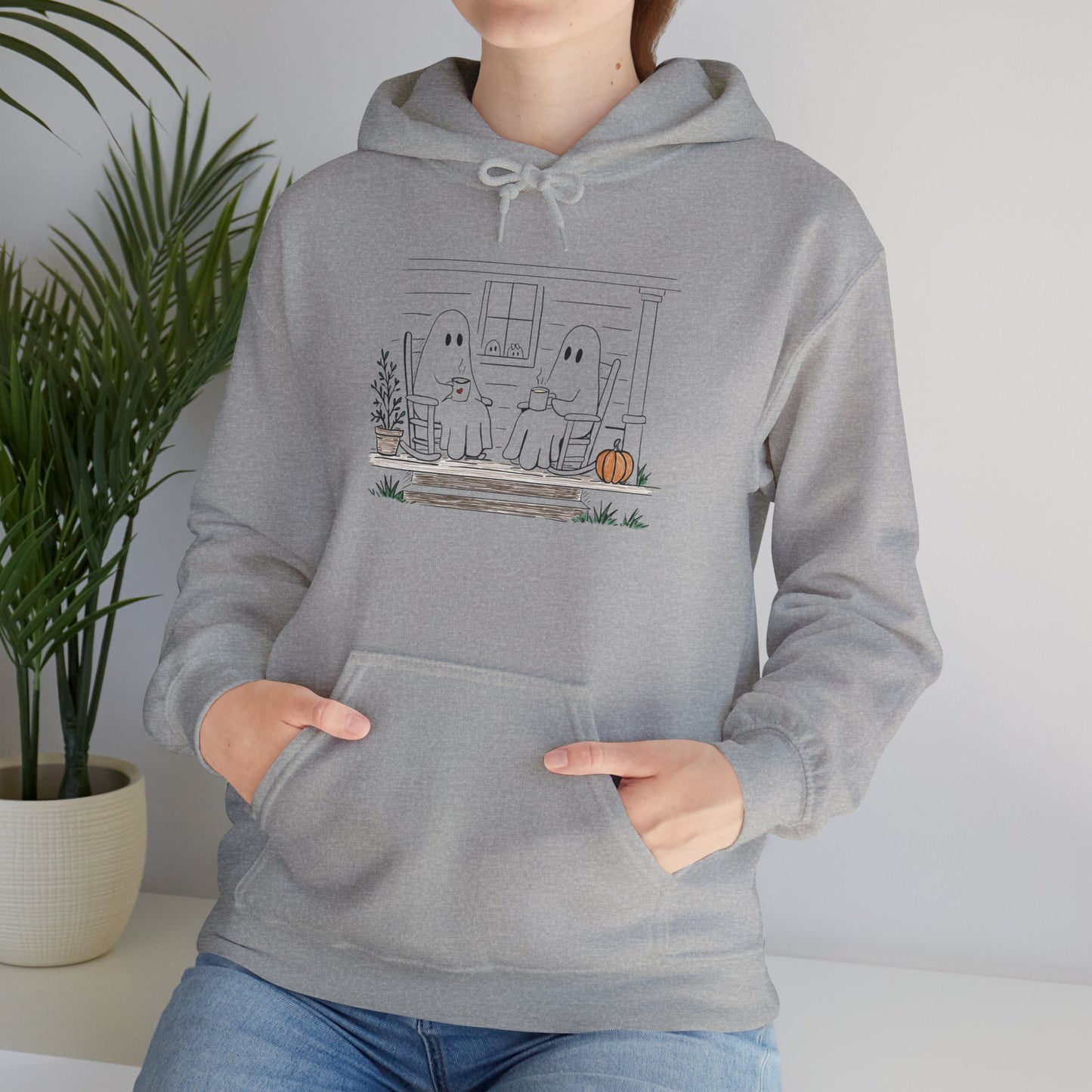 Pullover hoodie featuring a hand-drawn ghost family enjoying coffee in rocking chairs on a front porch, with two little ghosts peeking through the window, a pumpkin, and subtle fall color accents.