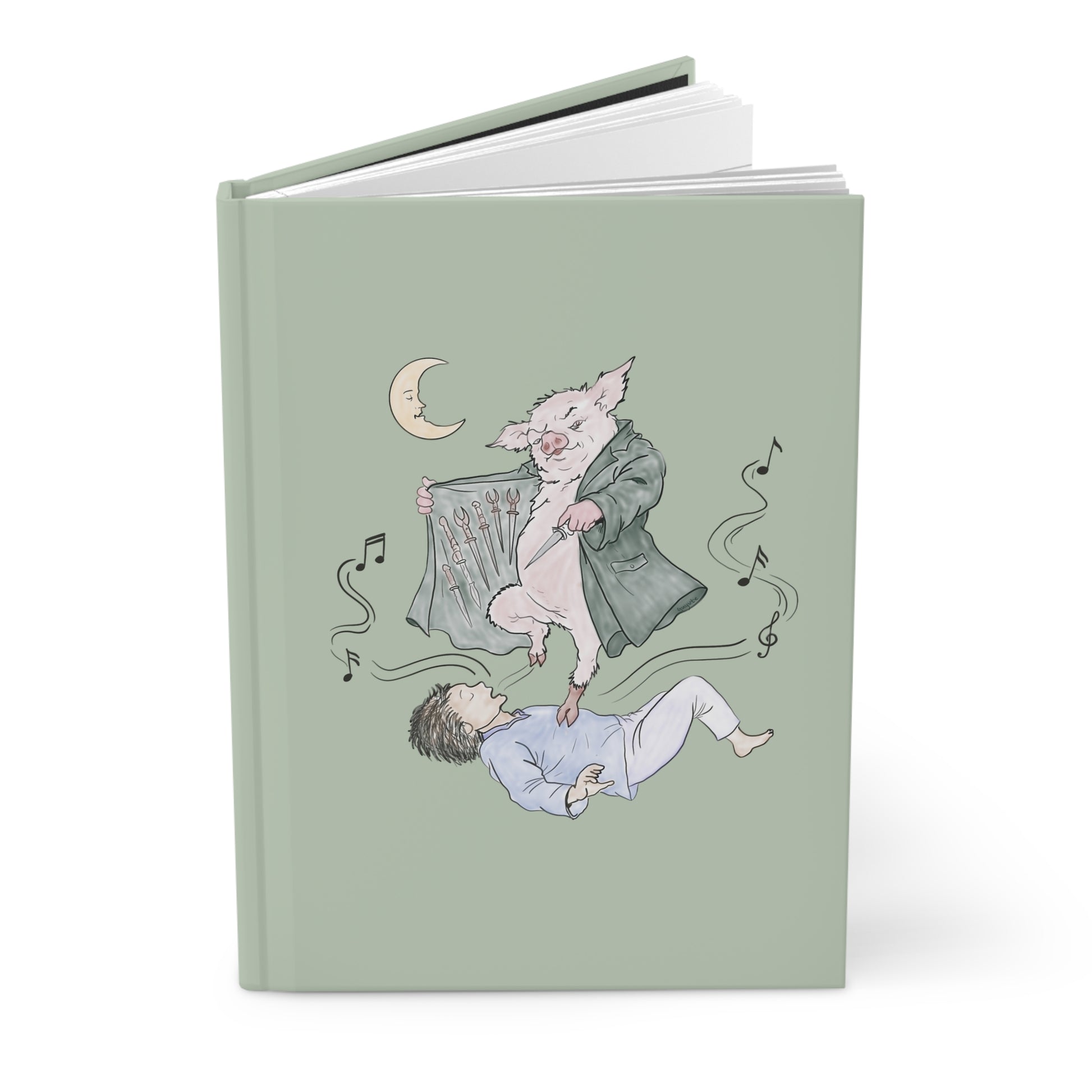 A hardcover journal with a sage green cover featuring a whimsical illustration of a pig in a coat floating above a sleeping person, with a crescent moon and musical notes.