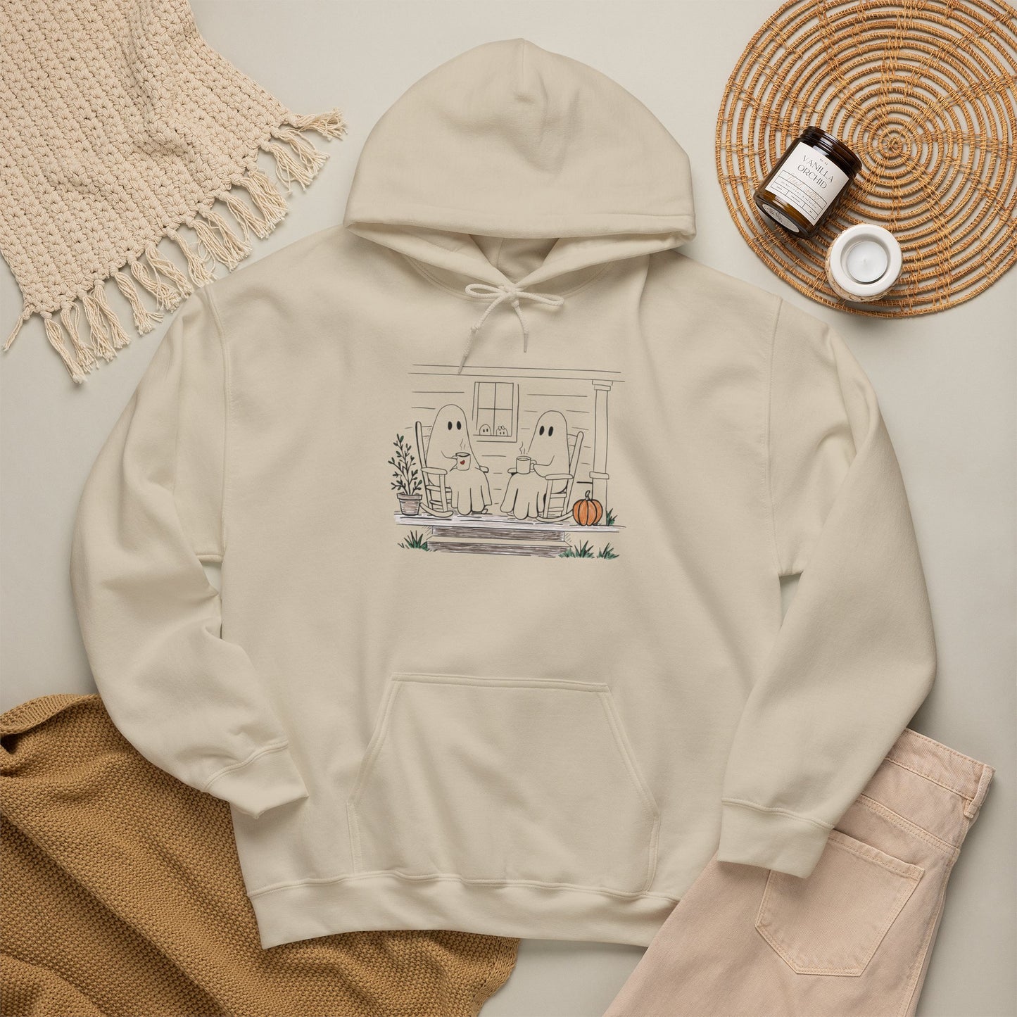 Pullover hoodie featuring a hand-drawn ghost family enjoying coffee in rocking chairs on a front porch, with two little ghosts peeking through the window, a pumpkin, and subtle fall color accents.