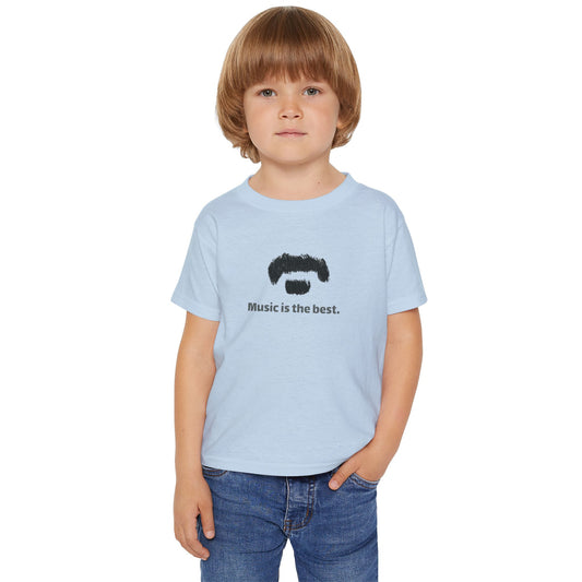 A young child with light brown hair wearing a light blue t-shirt with a black graphic of a mustache and beard and the text 'Music is the best.' paired with blue jeans, set against a plain white background.