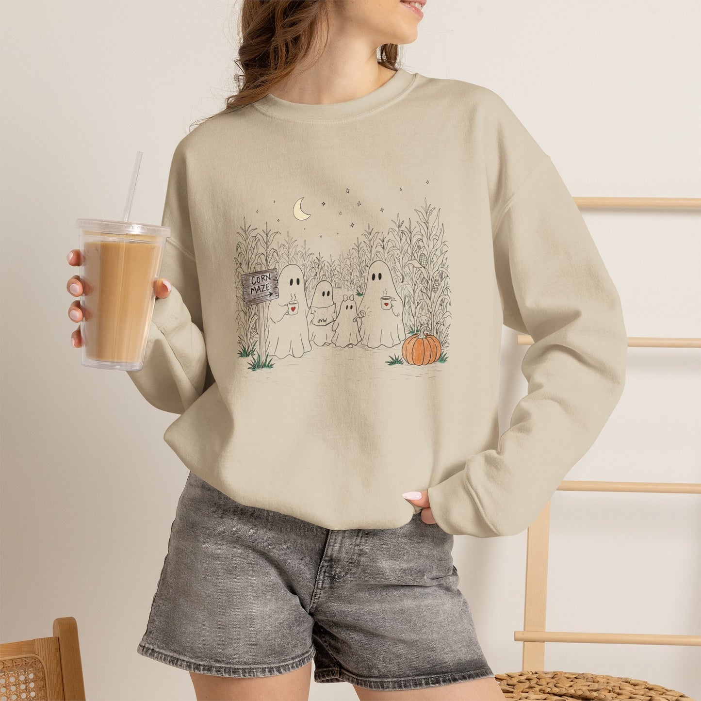 Crewneck sweatshirt featuring a hand-drawn ghost family walking through a moonlit corn maze with warm drinks, tall corn stalks, and a pumpkin from The Story of the Ghost Chapter 2 collection.