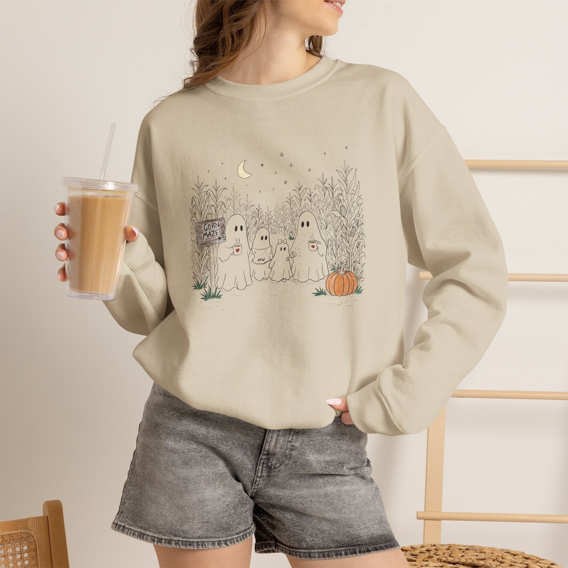 Crewneck sweatshirt featuring a hand-drawn ghost family walking through a moonlit corn maze with warm drinks, tall corn stalks, and a pumpkin from The Story of the Ghost Chapter 2 collection.