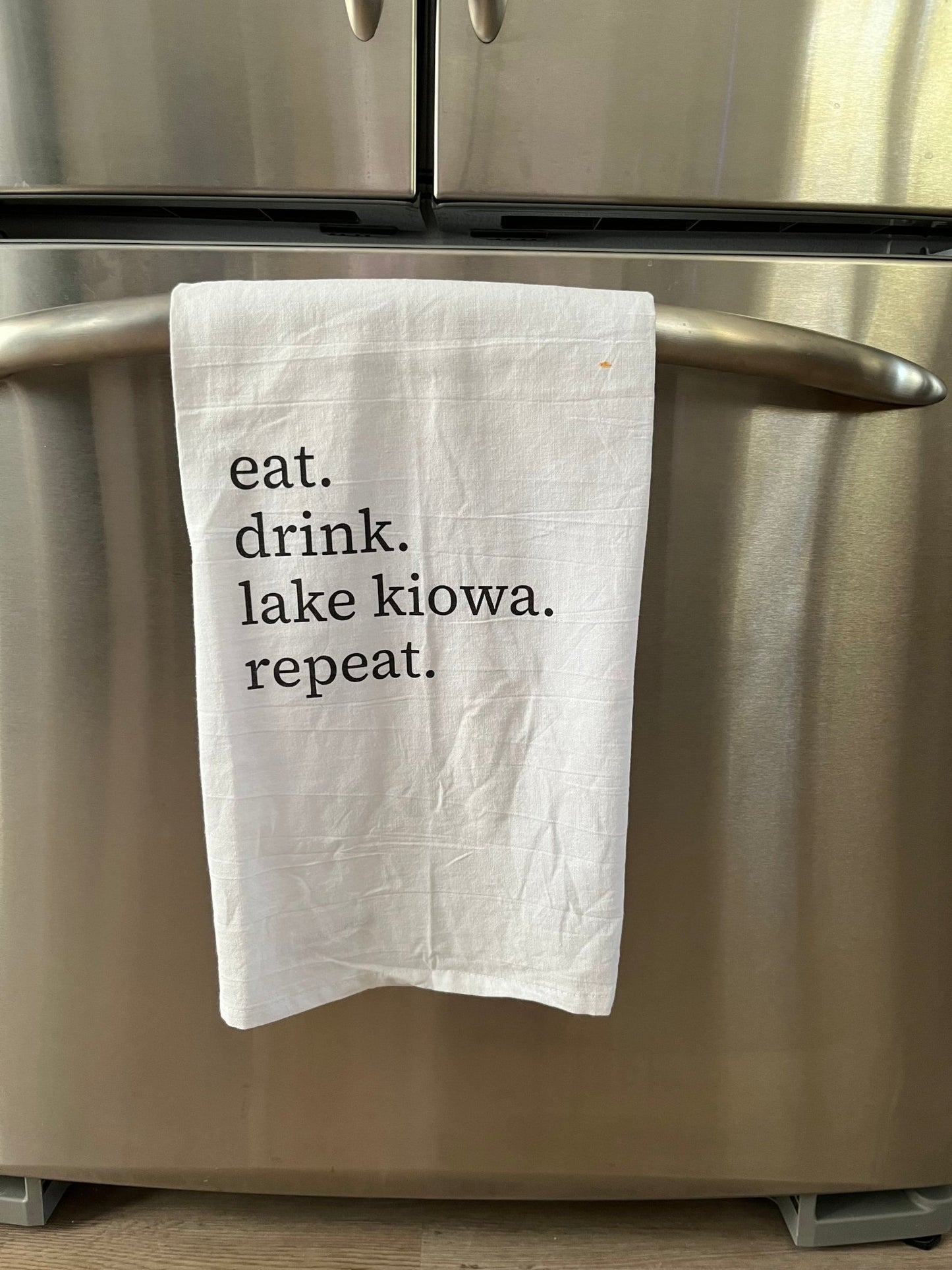 White towel with text hanging on a metallic  refrigerator