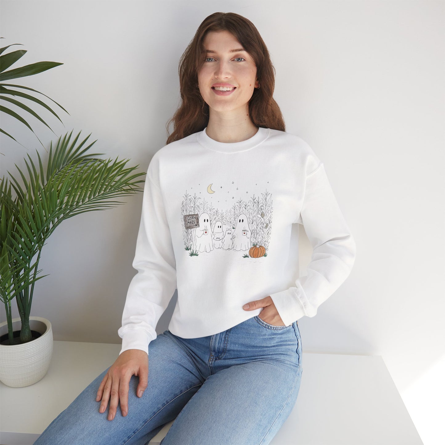 Crewneck sweatshirt featuring a hand-drawn ghost family walking through a moonlit corn maze with warm drinks, tall corn stalks, and a pumpkin from The Story of the Ghost Chapter 2 collection.