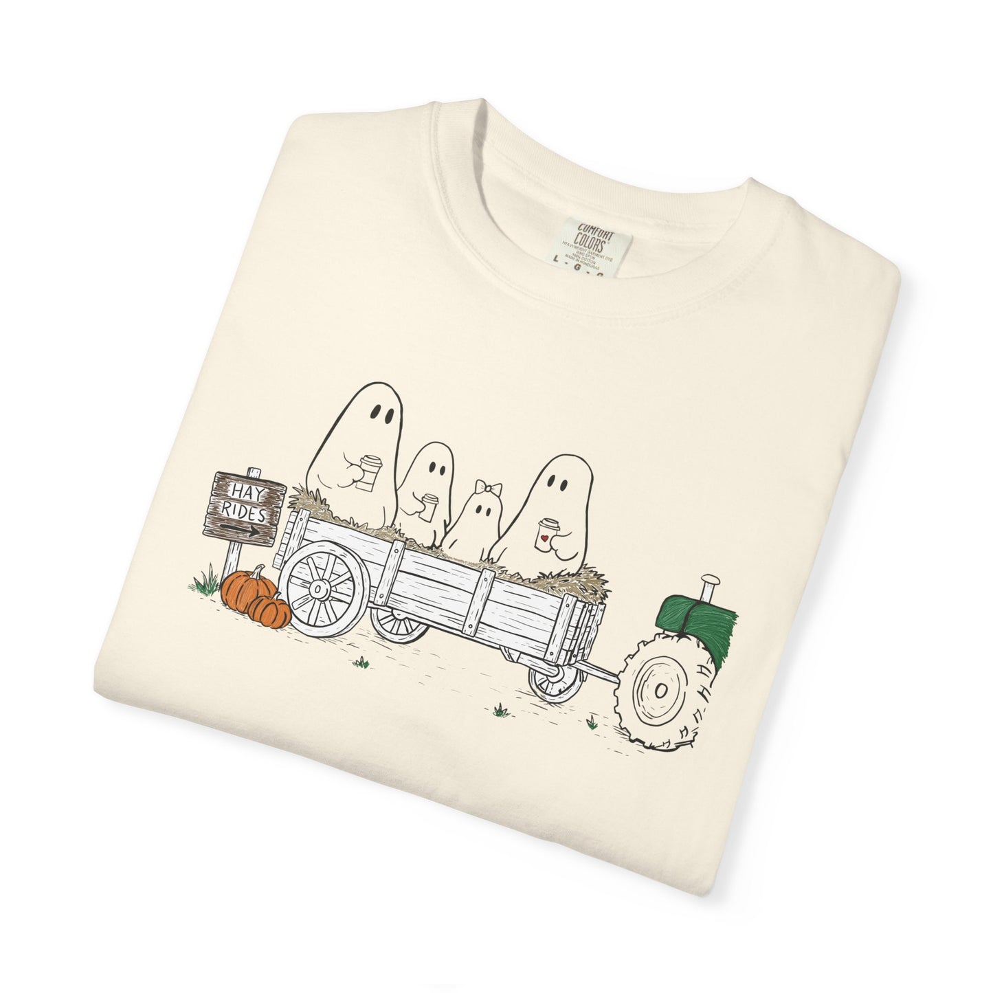 Comfort Colors ivory t-shirt featuring a hand-drawn ghost family riding in a hay wagon with pumpkins, coffee mugs, and a vintage tractor from The Story of the Ghost Chapter 1 collection.