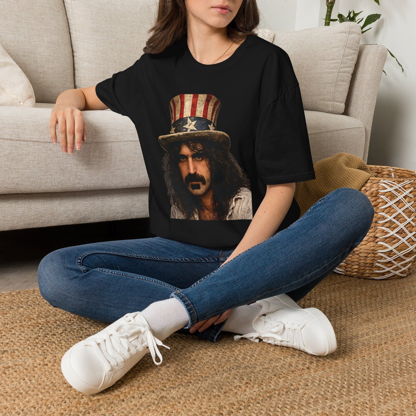 Person wearing a black t-shirt with a graphic design, sitting on the floor in a living room.