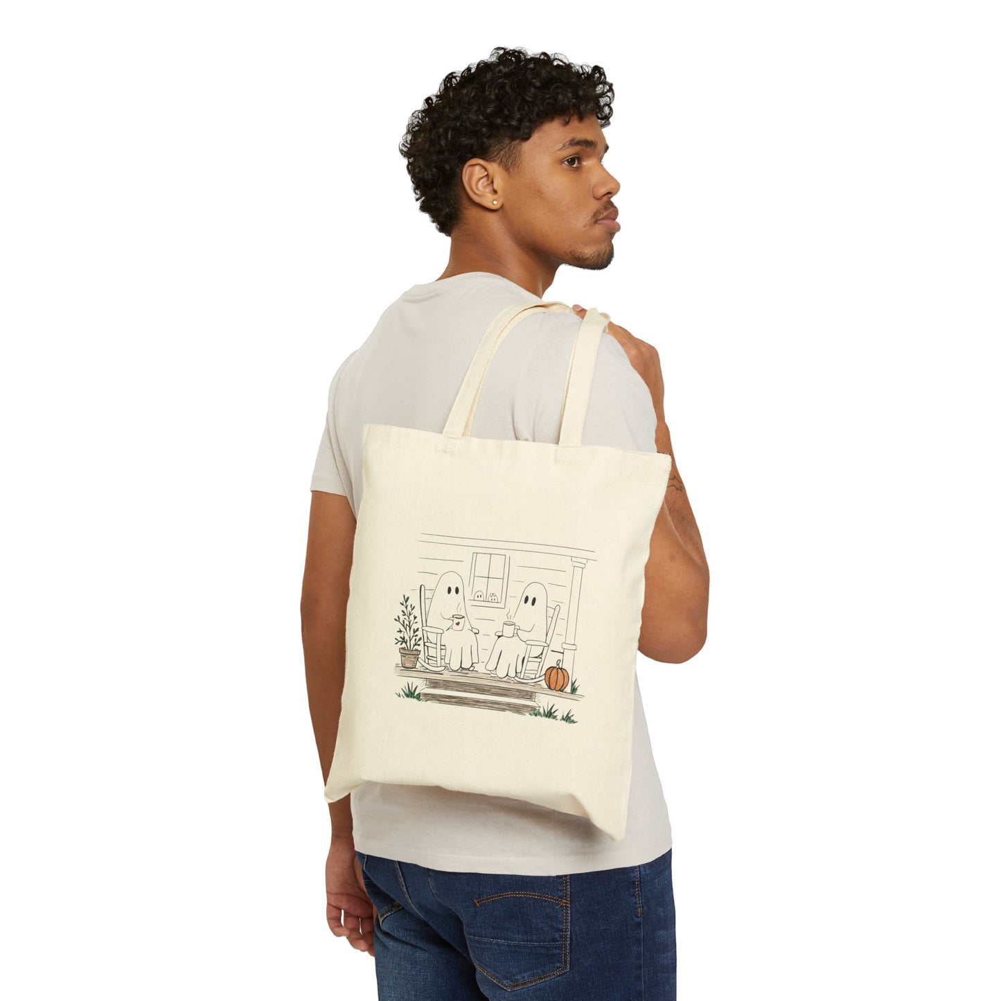 Natural canvas tote bag featuring a hand-drawn ghost family relaxing with coffee in rocking chairs on a front porch, with two little ghosts peeking through the window, a pumpkin, and subtle fall accents.