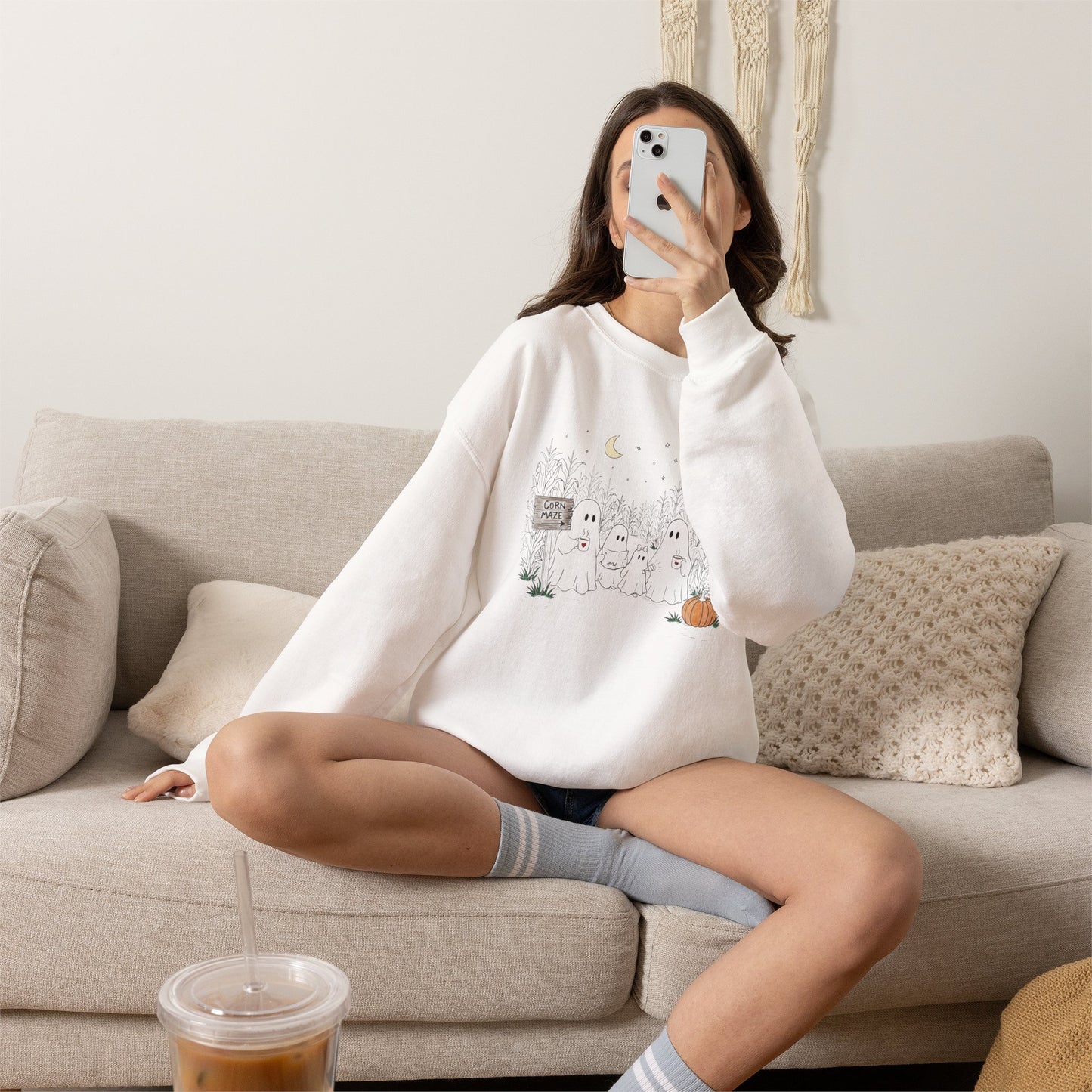 Person wearing a white sweatshirt with text, sitting on a couch in a living room.