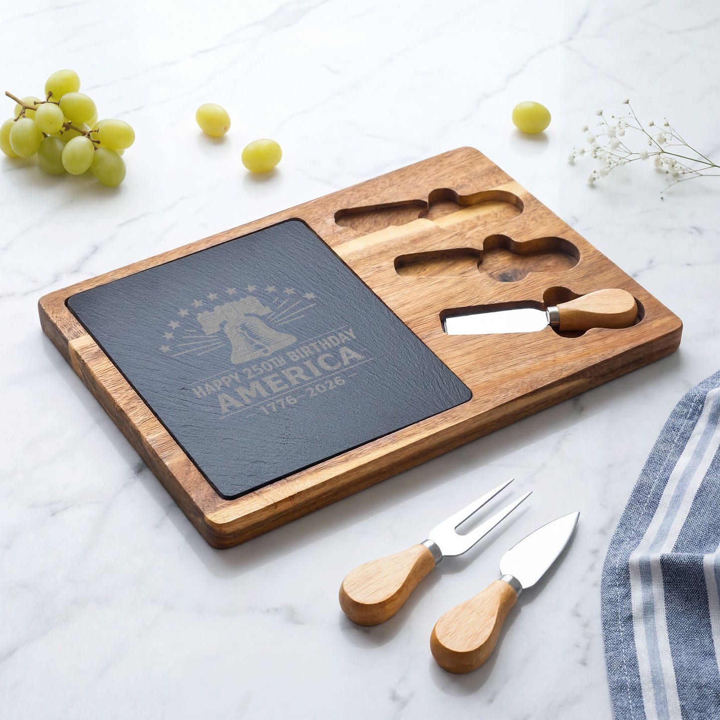 Wooden cutting board with engraved text, cheese knife, and fork on a marble surface.