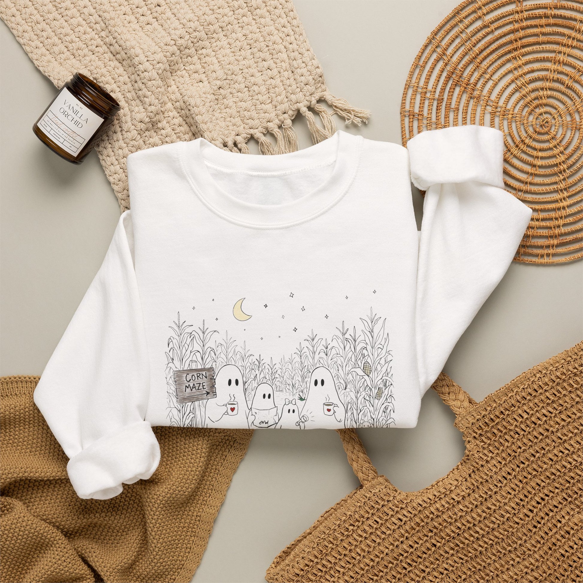 Crewneck sweatshirt featuring a hand-drawn ghost family walking through a moonlit corn maze with warm drinks, tall corn stalks, and a pumpkin from The Story of the Ghost Chapter 2 collection.