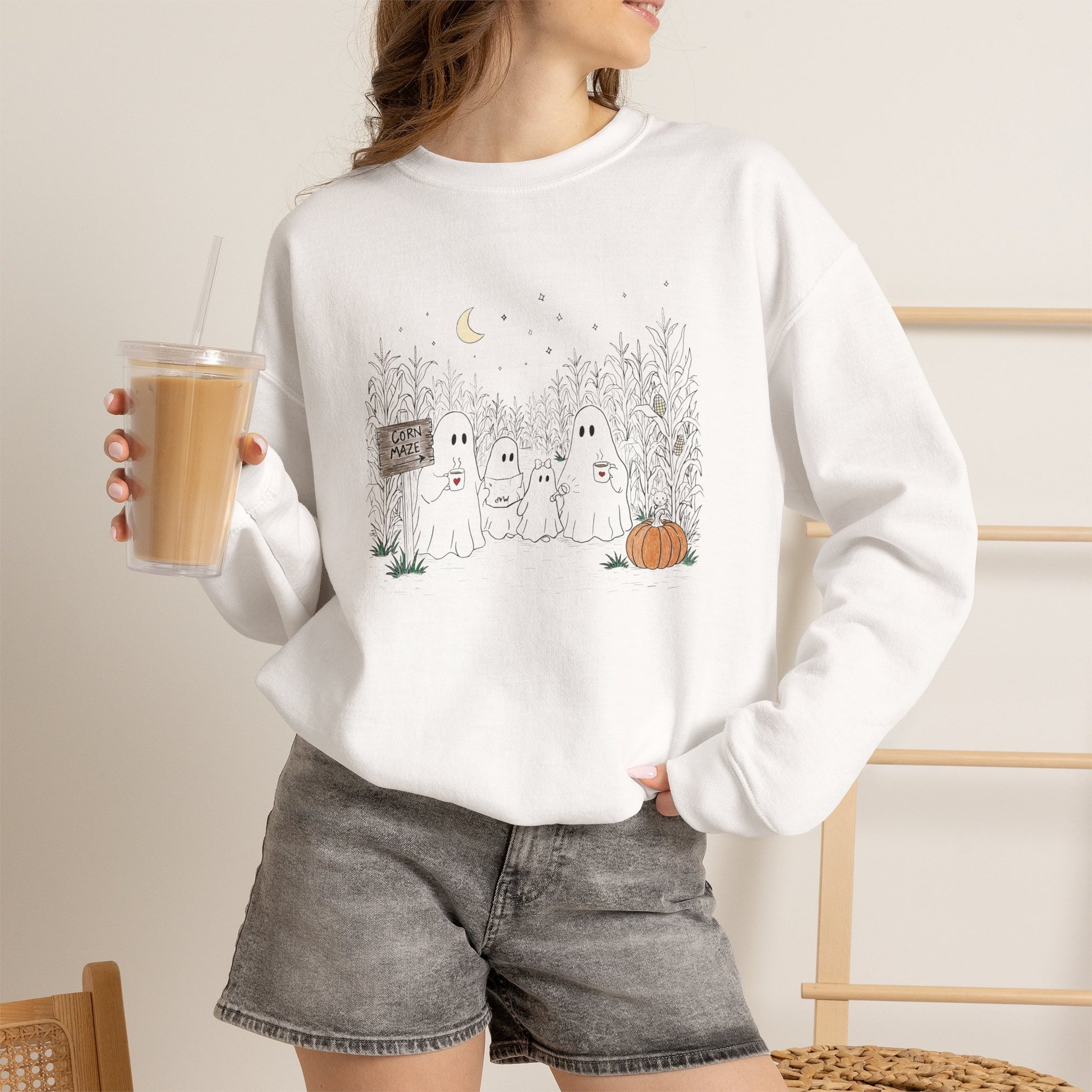 Person wearing a white sweatshirt with text and holding a coffee cup.