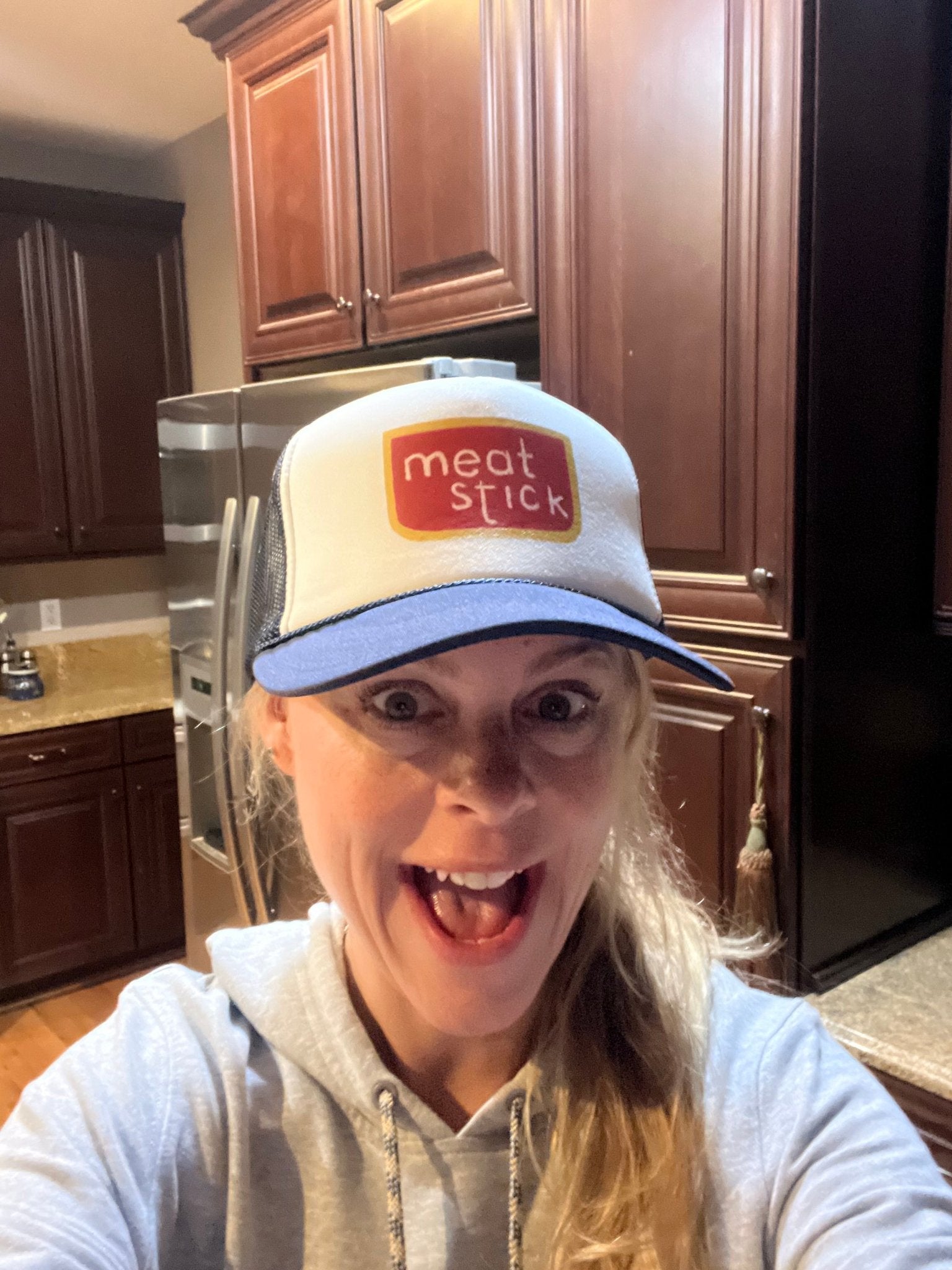 Person wearing a cap with 'meat stick' branding in a kitchen setting