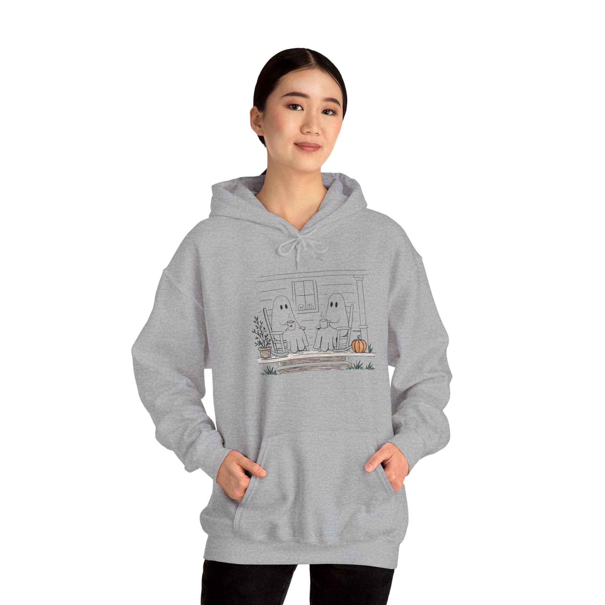 Pullover hoodie featuring a hand-drawn ghost family enjoying coffee in rocking chairs on a front porch, with two little ghosts peeking through the window, a pumpkin, and subtle fall color accents.