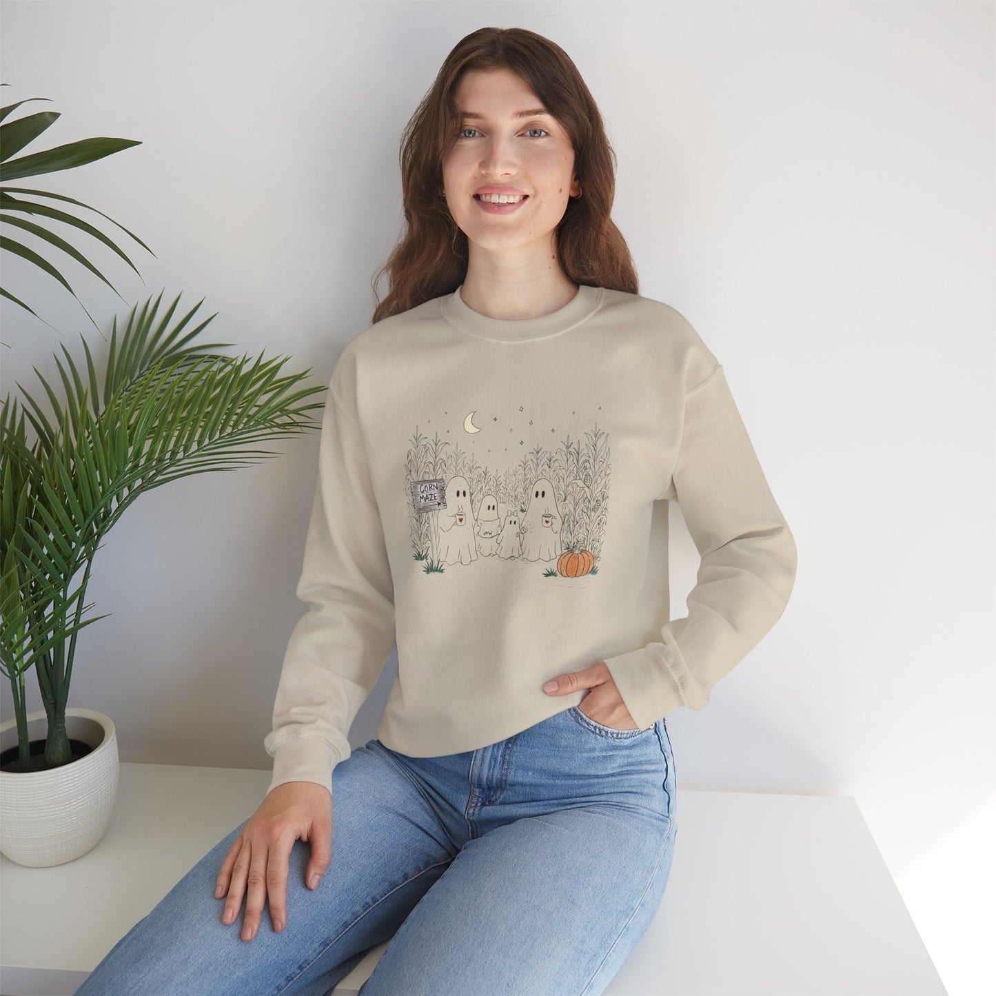 Crewneck sweatshirt featuring a hand-drawn ghost family walking through a moonlit corn maze with warm drinks, tall corn stalks, and a pumpkin from The Story of the Ghost Chapter 2 collection.