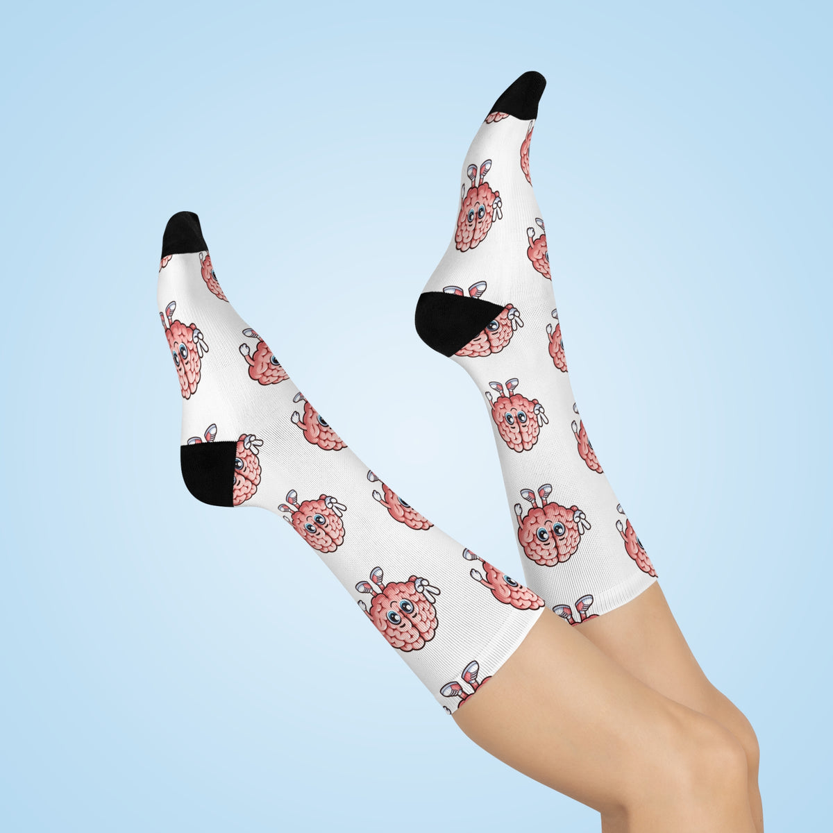 White crew socks with a pink cartoon brain character pattern and black toe/heel caps, shown on a person's legs against a light blue background.