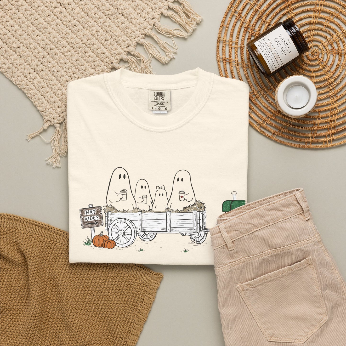 Comfort Colors ivory t-shirt featuring a hand-drawn ghost family riding in a hay wagon with pumpkins, coffee mugs, and a vintage tractor from The Story of the Ghost Chapter 1 collection.