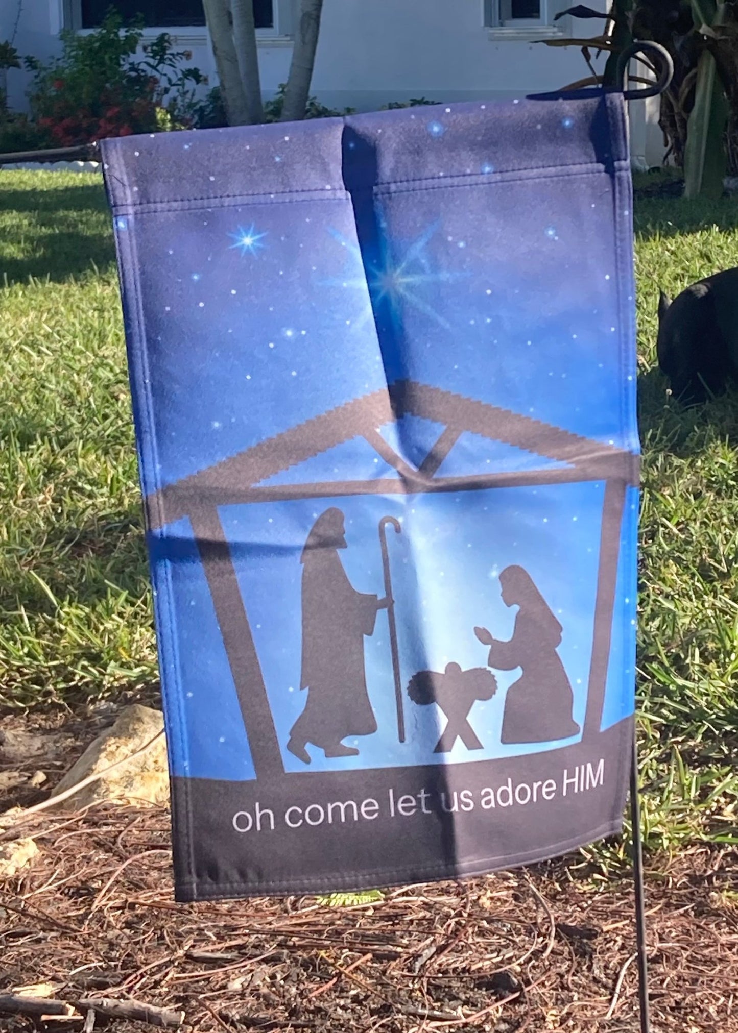 Nativity scene garden flag with 'oh come let us adore HIM' text on a grassy background
