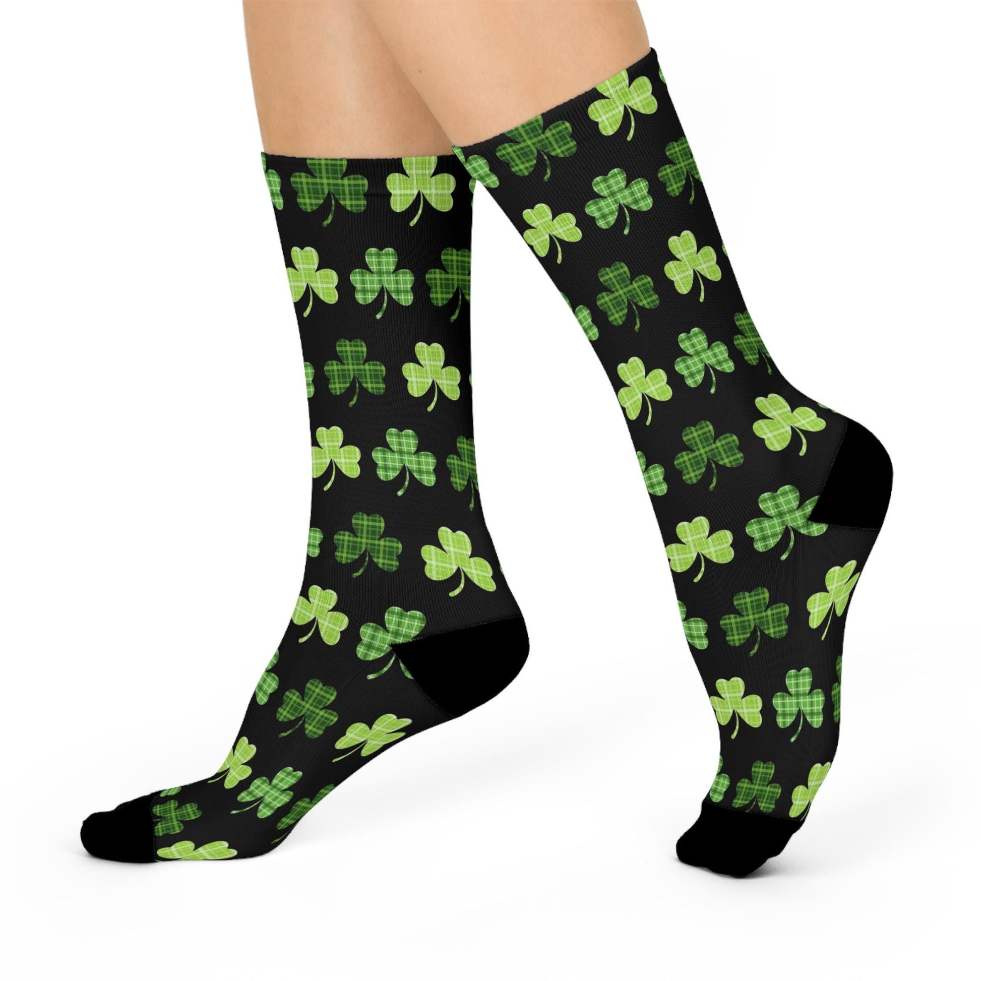 A pair of black crew socks with an all-over green clover print, standing upright.