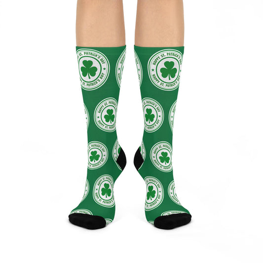 A pair of green crew socks with shamrock designs, displayed on a model's feet.
