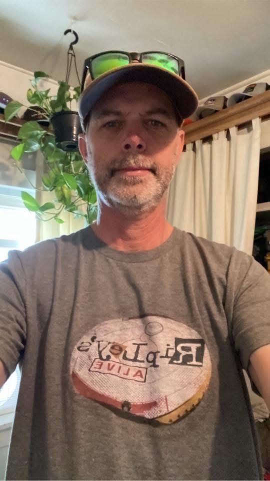 Man wearing a gray t-shirt with a logo indoors